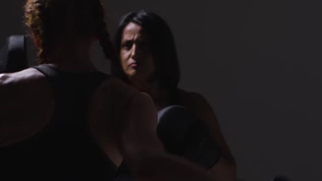 Close-Up-Studio-Shot-Of-Two-Mature-Women-Wearing-Gym-Fitness-Clothing-Exercising-Boxing-And-Sparring-Together-3